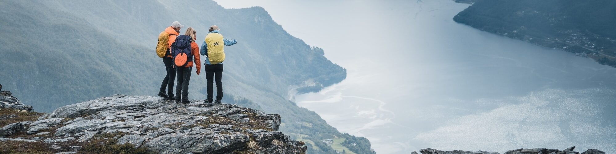Drei Personen auf einem Berg mit Blick auf den Fjord