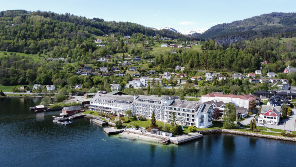Bird-view panoramic picture of a white hotel building by the fjord.