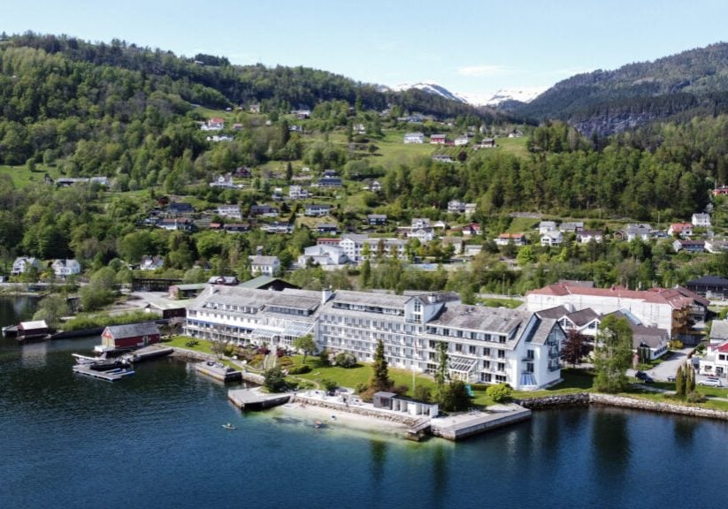Bird-view panoramic picture of a white hotel building by the fjord.