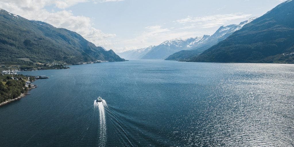 Hardangerfjord Cruise_Norled_Visit Hardangerfjord Boat seen sailing on the Hardangerfjord from behind on a sunny summer day.