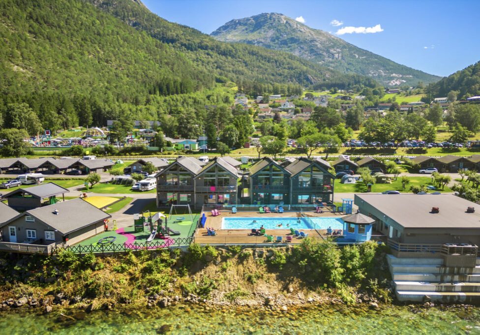 A holiday resort with swimming pool and mountains int he background.