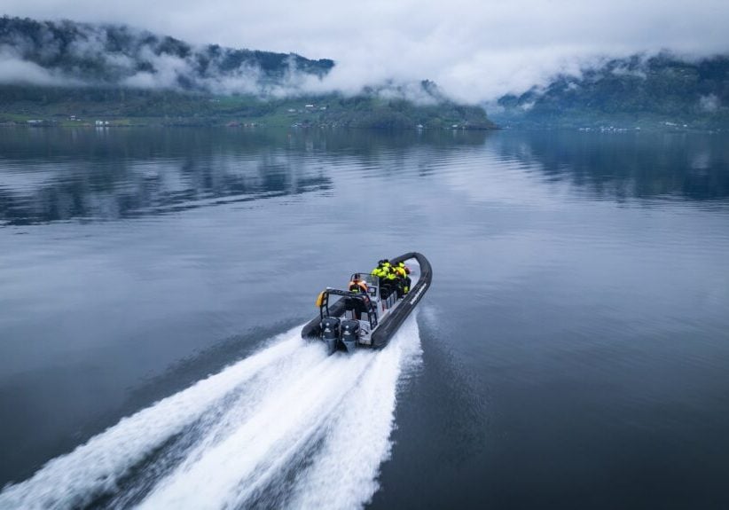 RIB boat cruising on a fjord on a cloudy day.